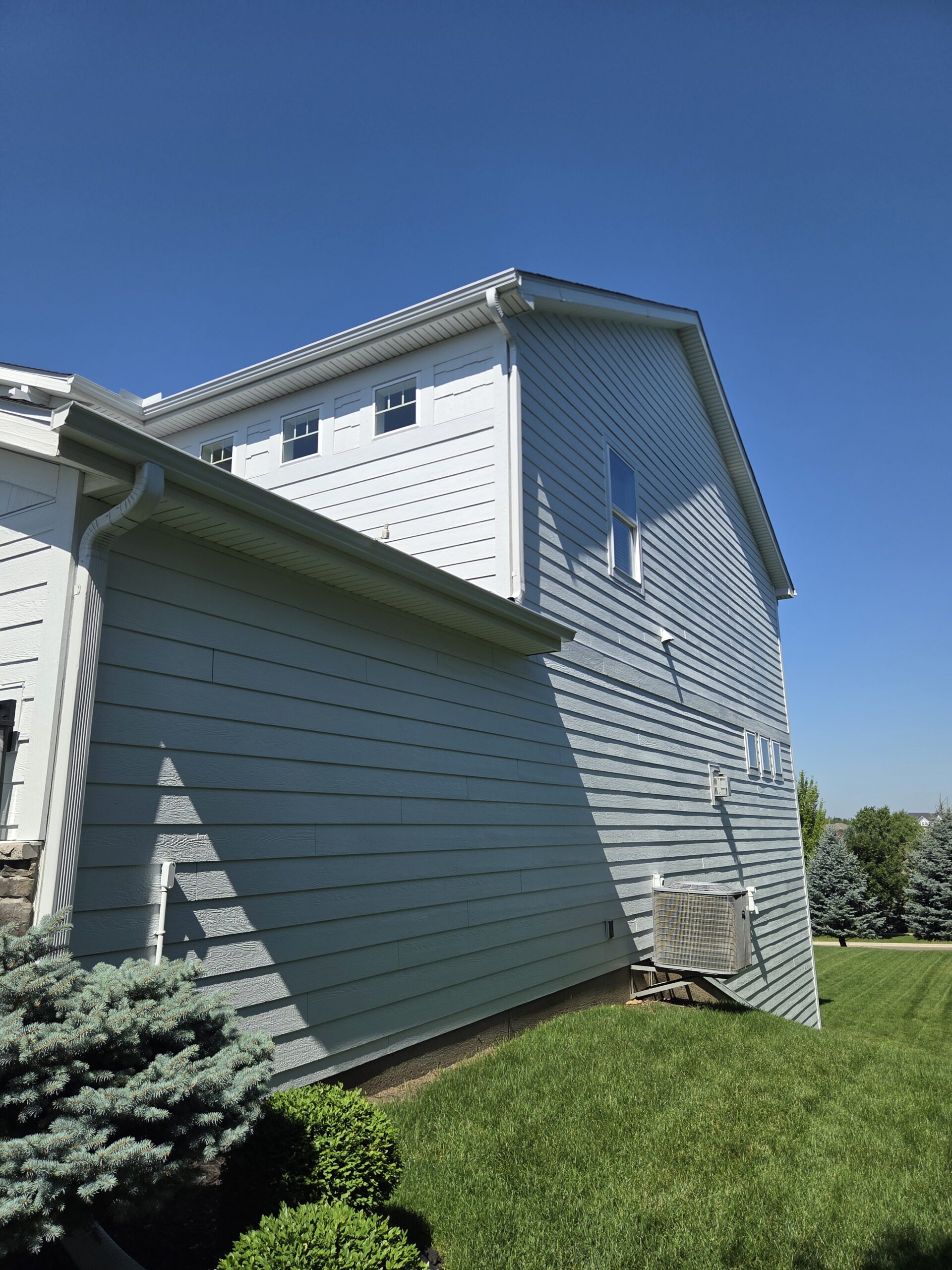 Side elevation with freshly painted lap siding, white trim, soffits, and gutters