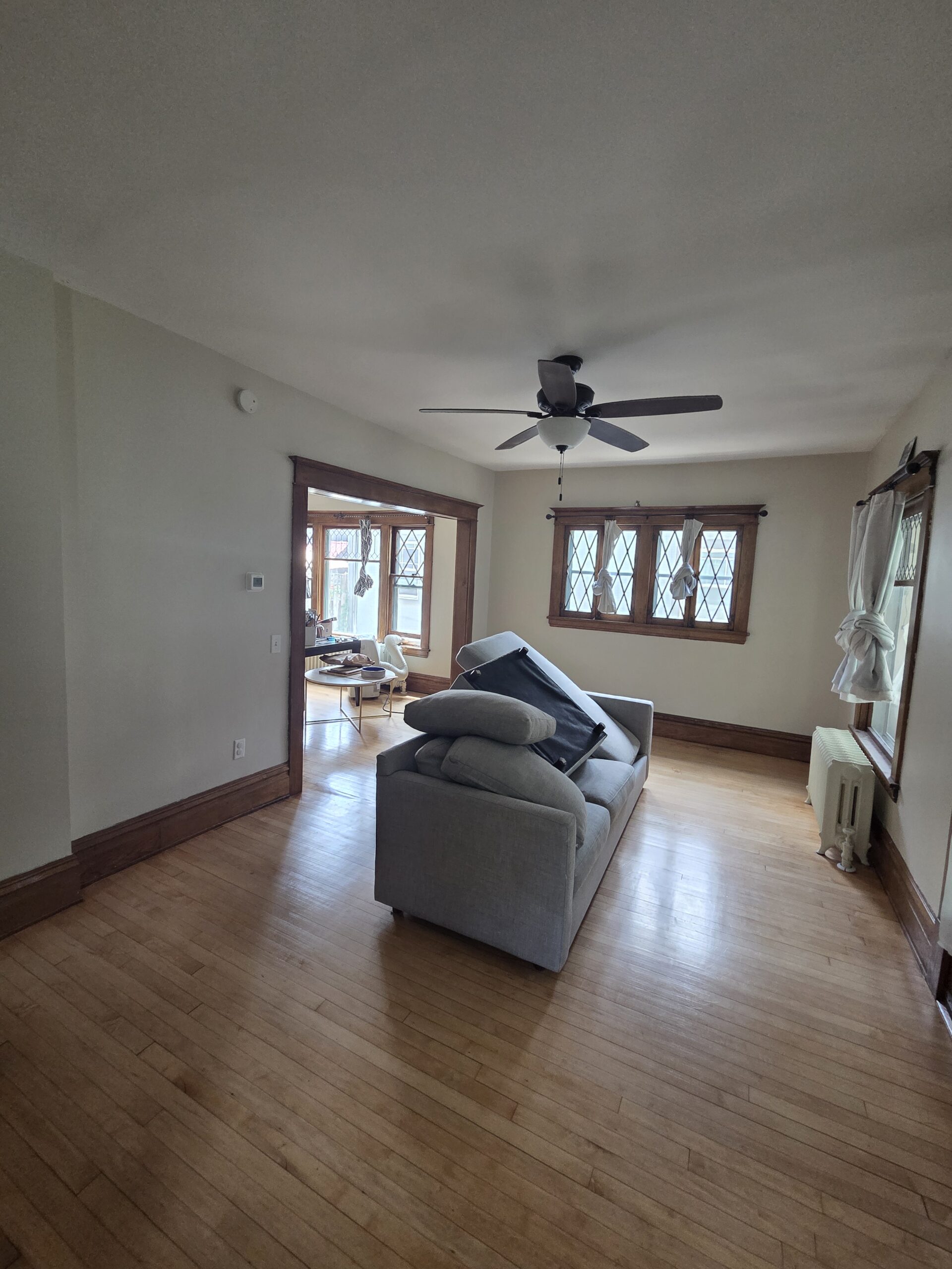 Living room with freshly painted walls and ceiling and clean cut lines against original stained wood trim and leaded windows