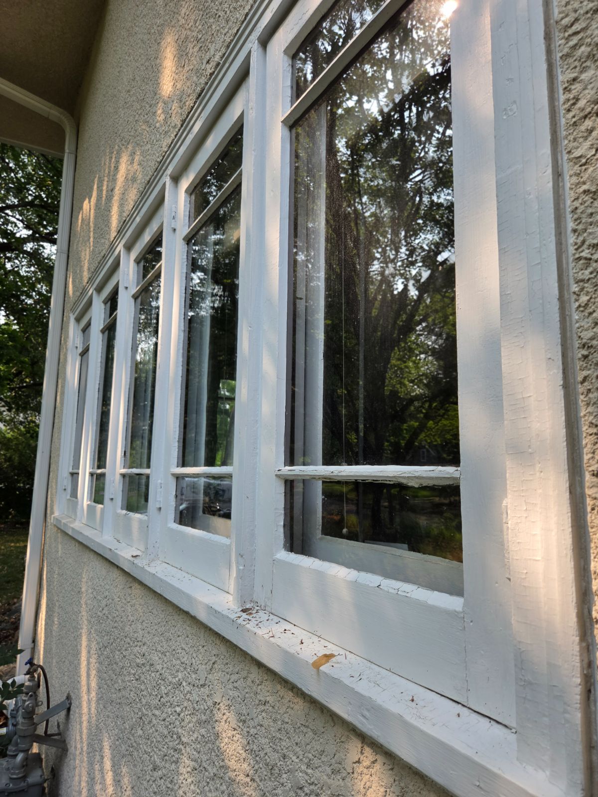 Weathered window trim with cracked, peeling paint on a stucco house before exterior prep