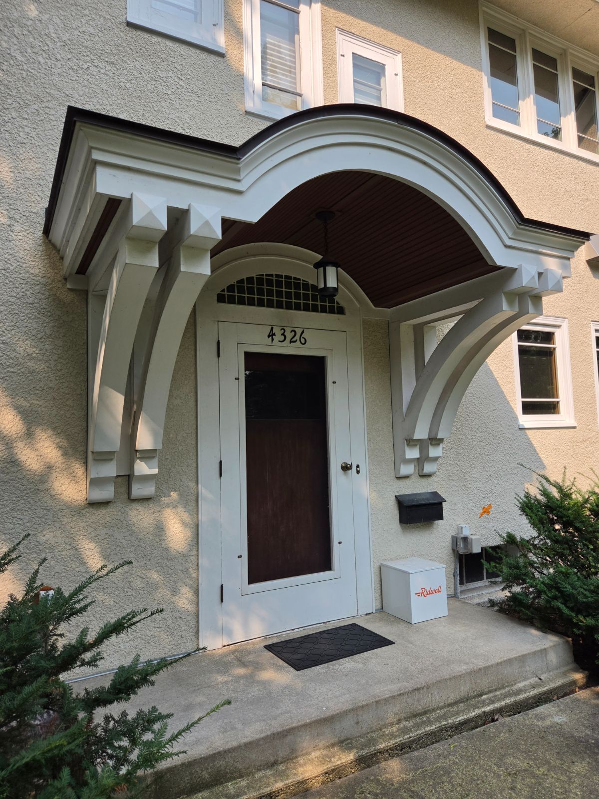 Arched entry canopy, brackets, and door trim with a crisp white premium finish on a stucco home