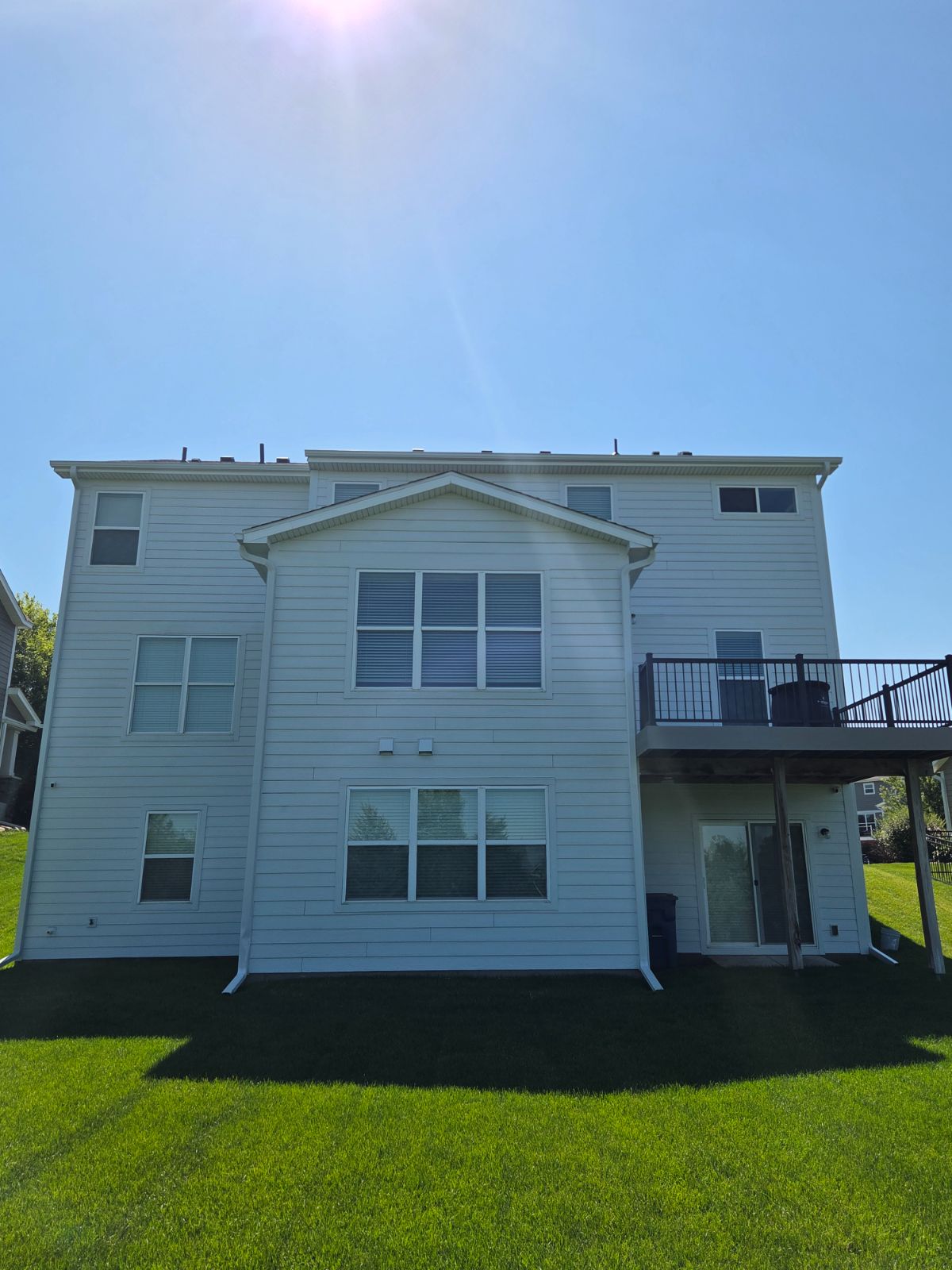 Rear of a three-story home with freshly painted white lap siding and trim